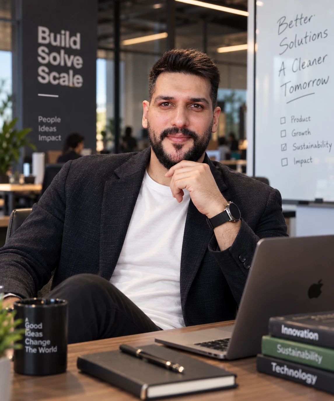 Raad Al-Qudah in a dark blazer and white t-shirt at his desk in an open-plan office
